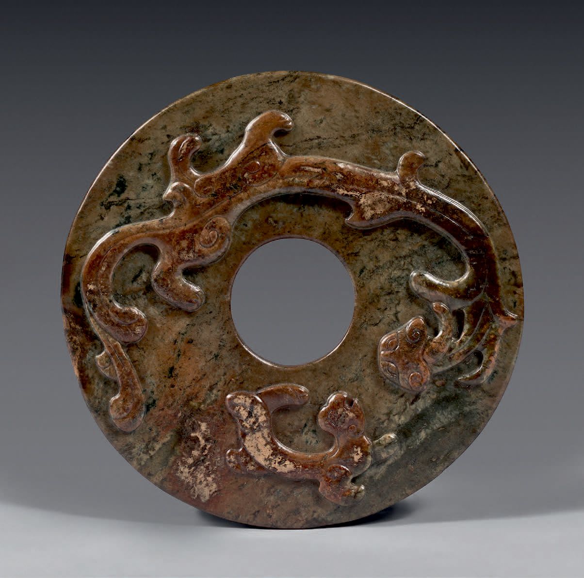CHINE - Époque Ming (1368-1644) 绿褐色的玉（软玉）"璧 "盘，浮雕有两条赤龙。
(碎片）。
D: 17 cm