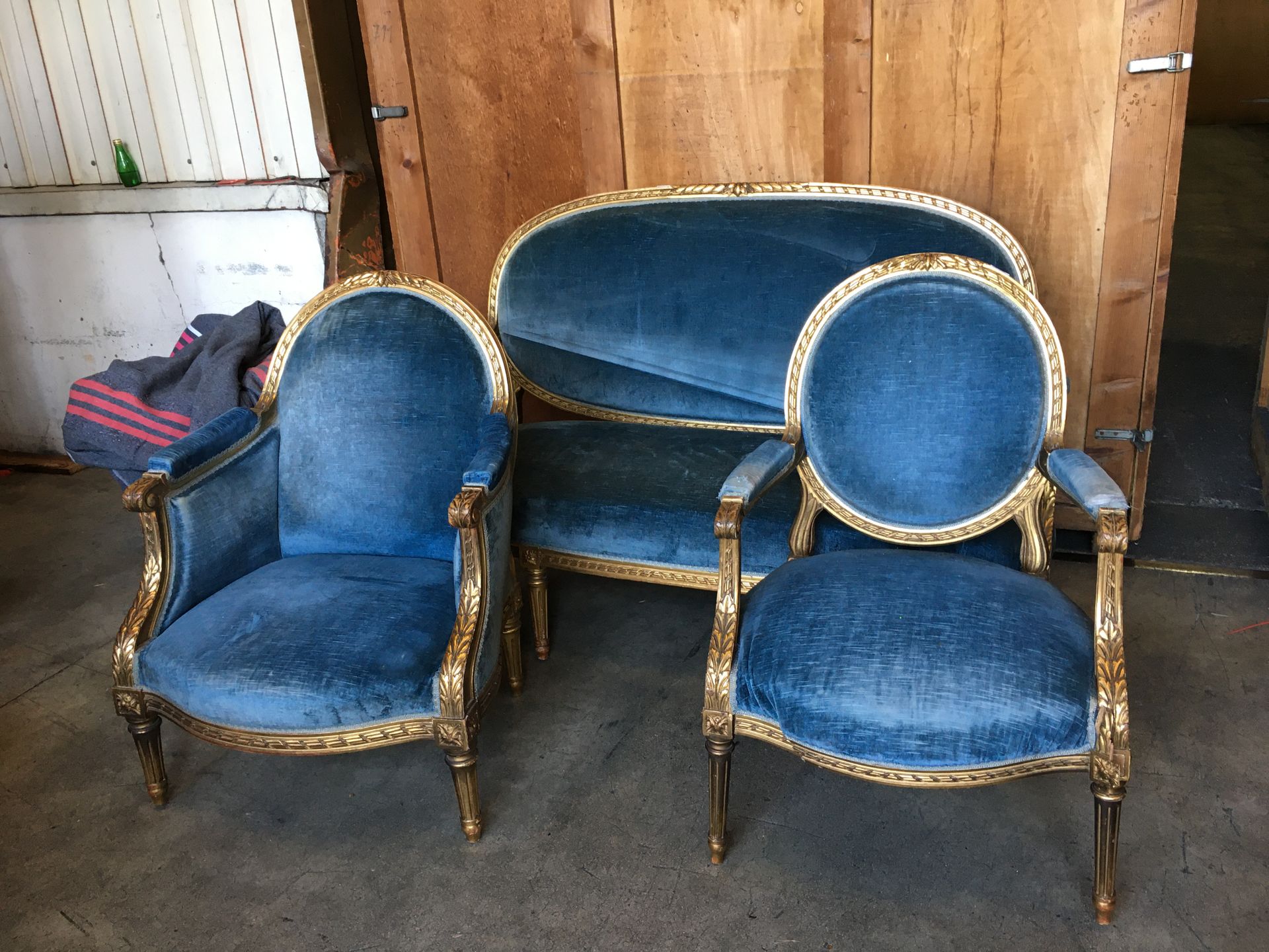 Null 路易十六风格的客厅雕刻和镀金木家具，包括：沙发，两把扶手椅和两把贝格，装饰有叶子和带状花环，凹槽腿，蓝色天鹅绒软垫（一条腿损坏）参考49
