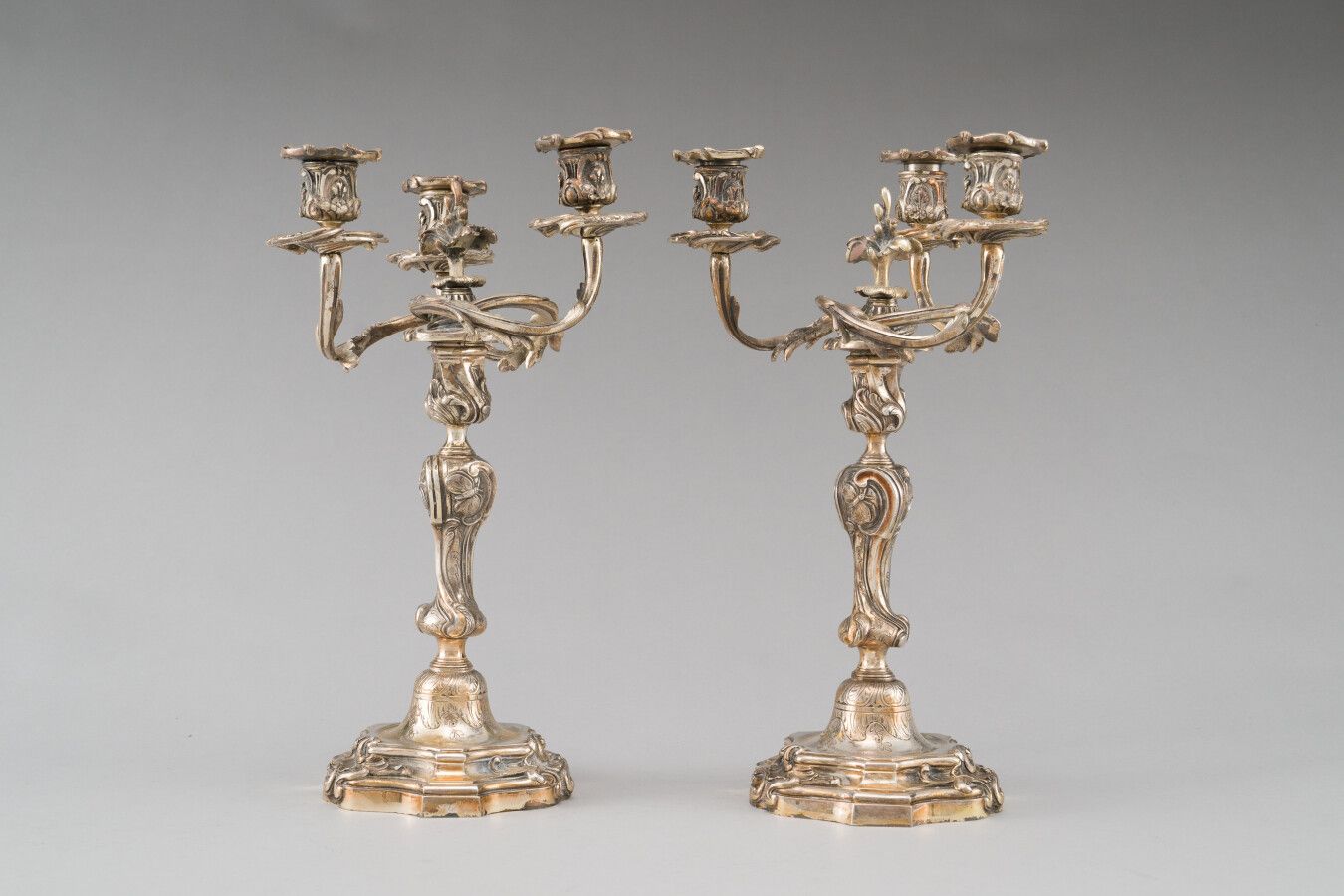 Null 一对镀银的三臂青铜烛台。模型有轮廓的边缘，下有扣子。卷曲的手臂是由叶子组成的。

19世纪晚期。

高度：37厘米。