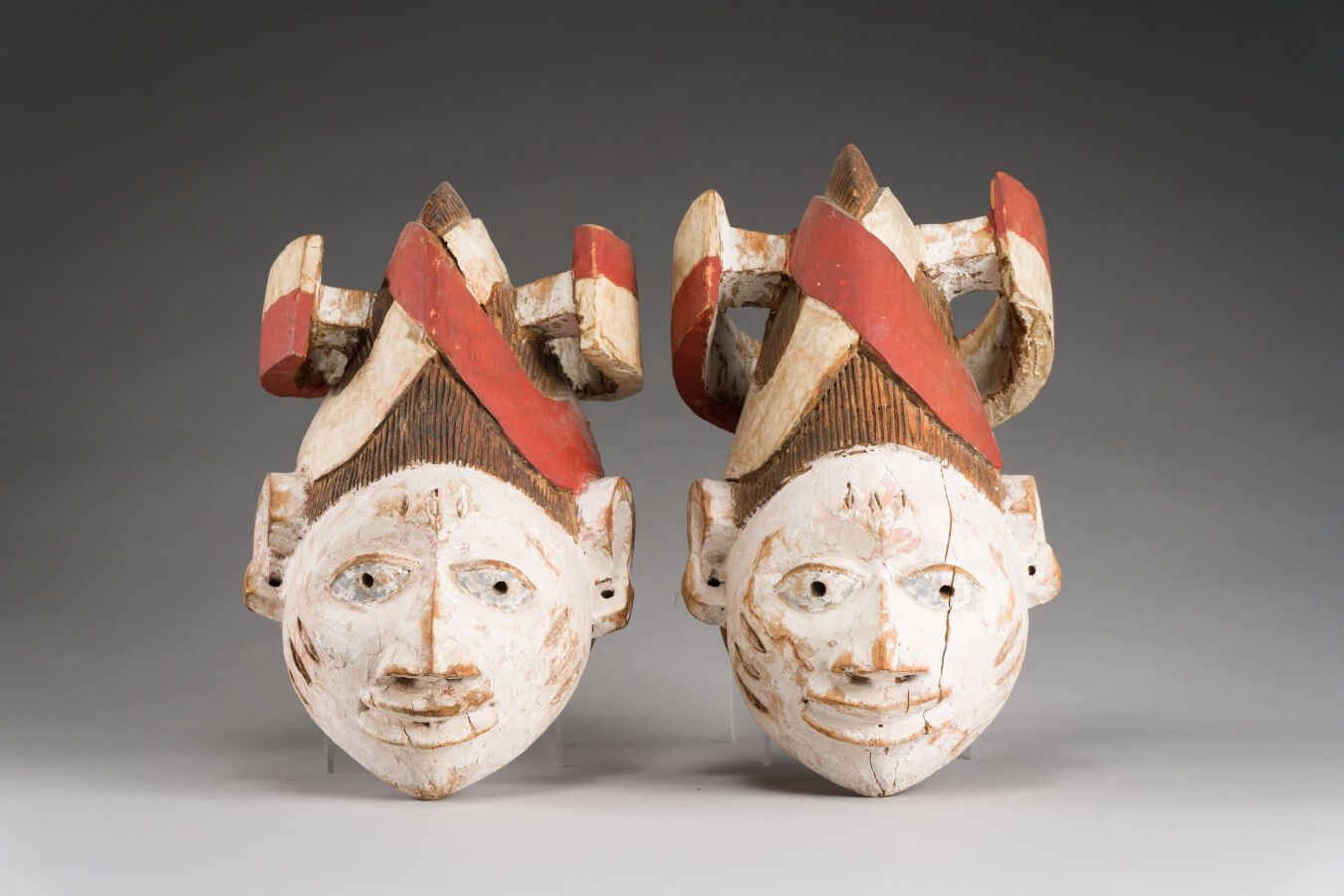 Null 68.一对Guélédé面具，面部有疤痕，头饰呈弧形排列。

多色木，有旧的铜锈和使用的痕迹。

约鲁巴人，尼日利亚，20世纪。

高：26和26.5&hellip;