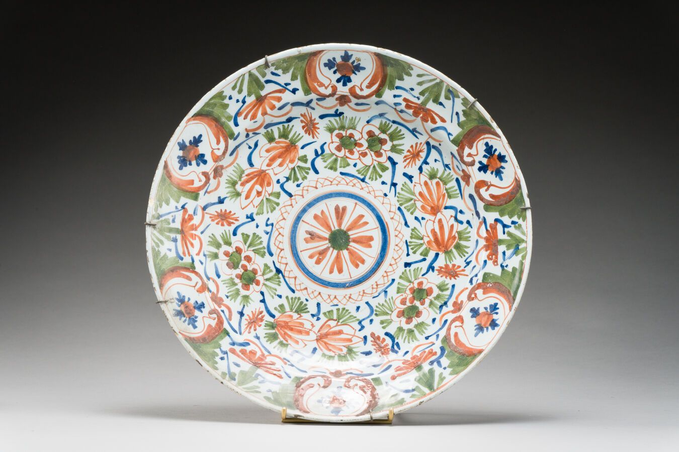 Null 161.DELFT

大型圆形陶盘，有多色的风格化花朵和卡图的装饰。

18世纪时期。

(Chips)。

D.35厘米