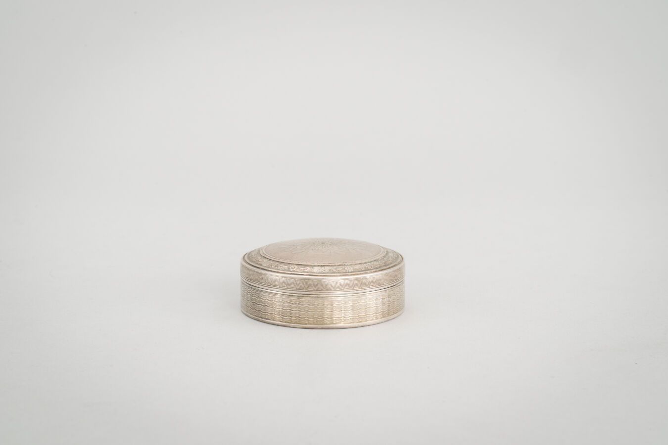 Null 74.一个圆形的银盒（800/1000），背景是玑镂式的风格化图案。

重量：45克