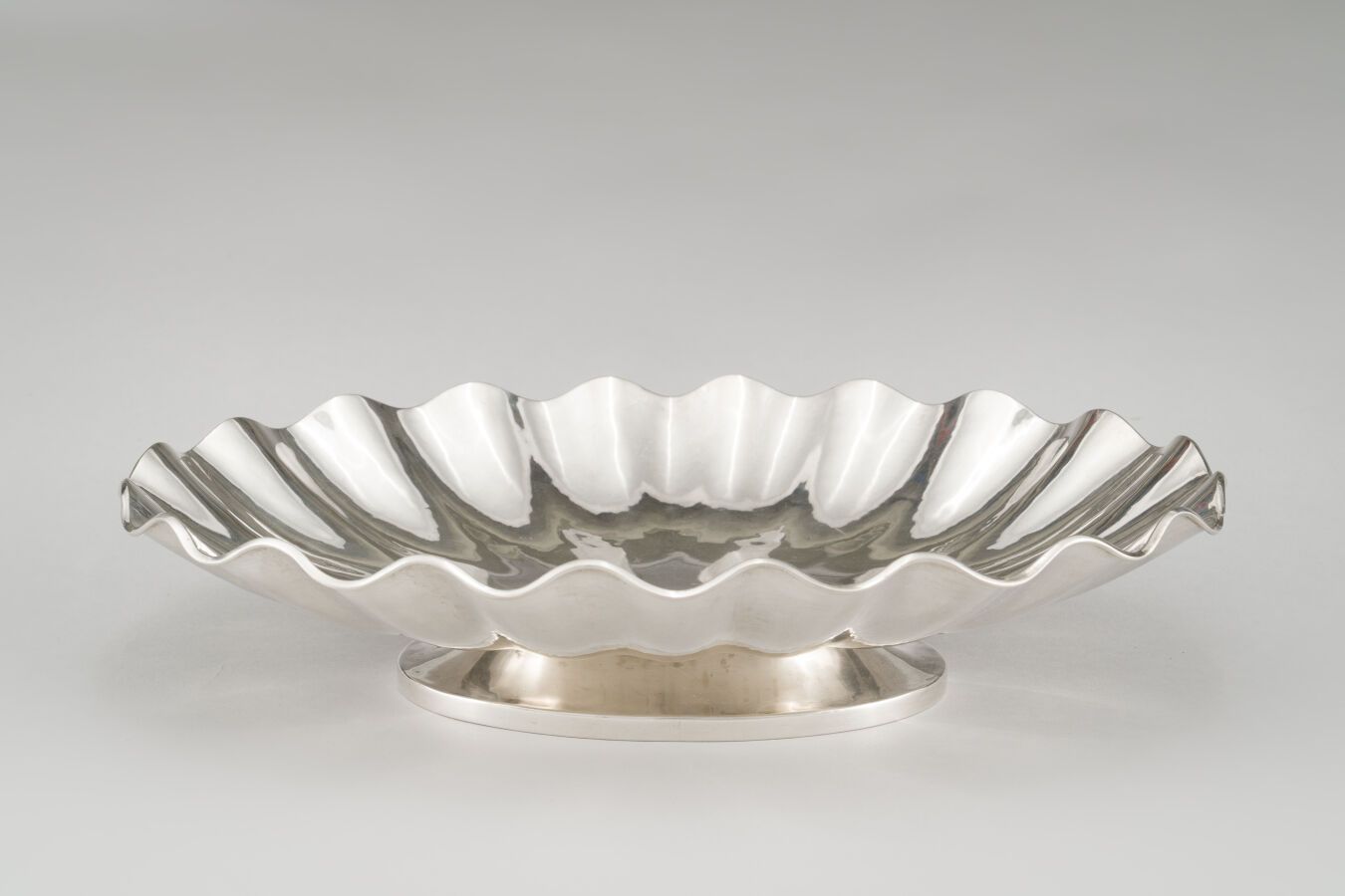 Null 一个锤子银（800/1000）的椭圆形碗，有扇形的边缘，放在一个成型的基座上。

重量：1250克。

意大利，20世纪。

长：42厘米。