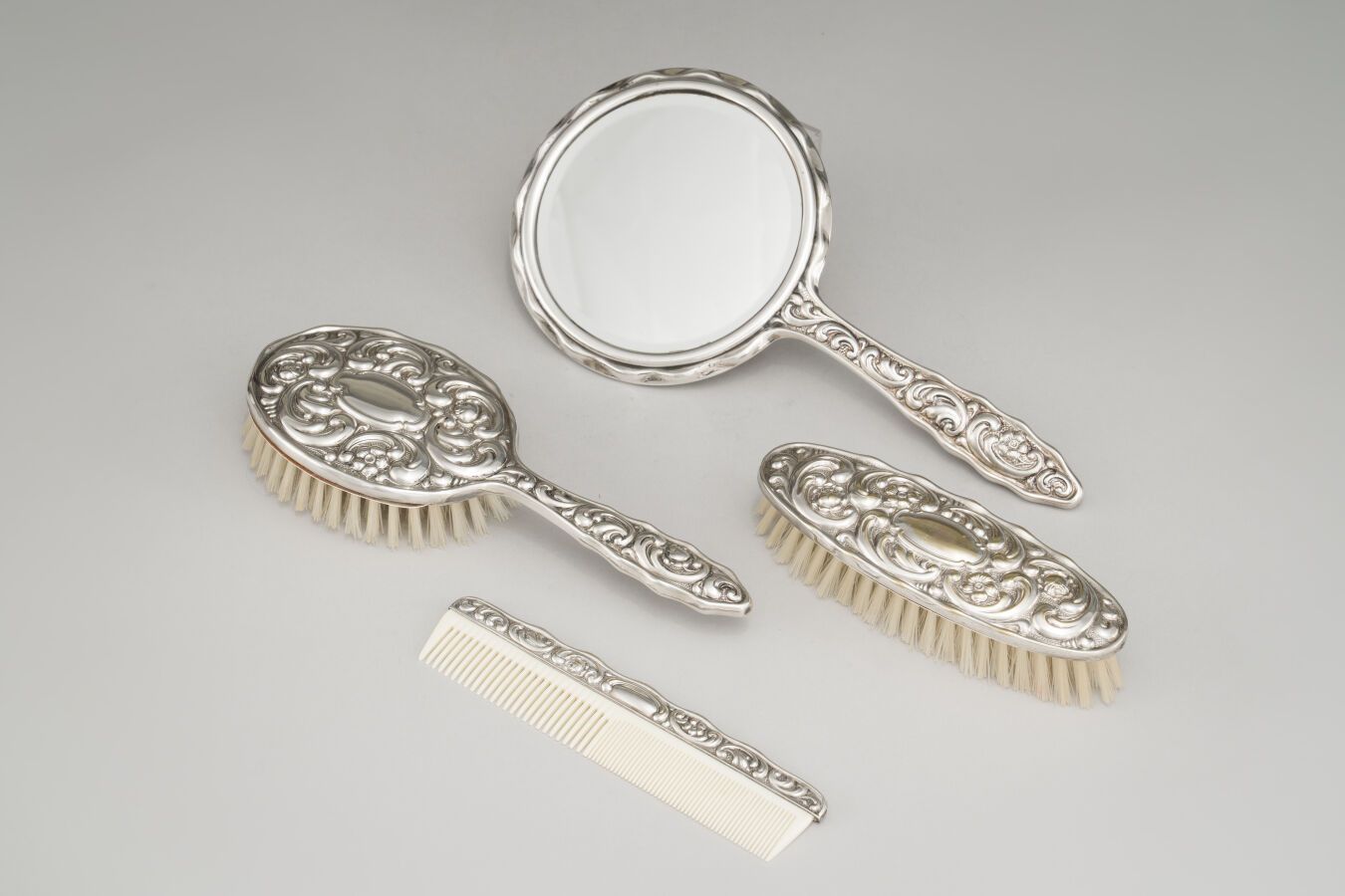 Null 一套镀银的梳妆台，有刺桐叶装饰，包括一把梳子，两把刷子和一张手脸。

外国作品，1900年后。

长：28厘米（用于倒立）。