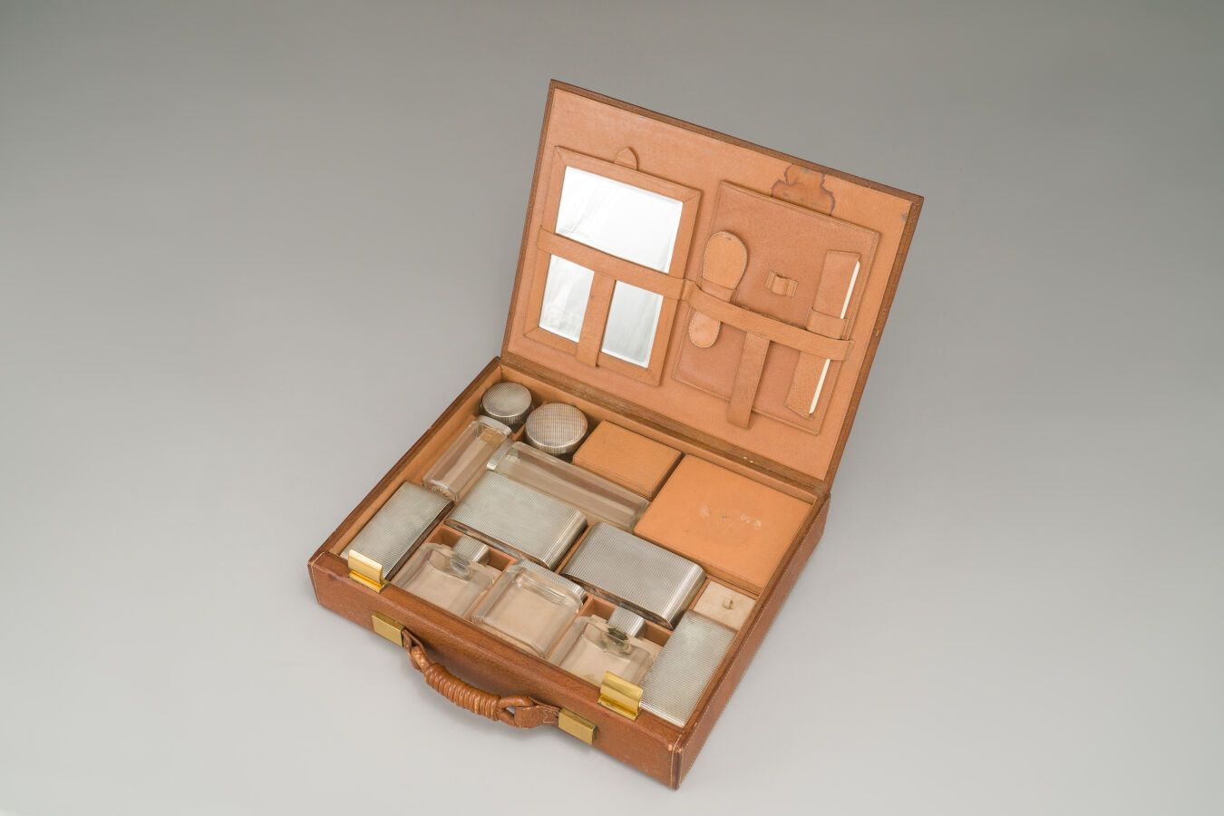 Null 旅行洗漱用品套装，包括一个棕色的皮箱，里面有七个刻面的水晶瓶，银制的（925/1000），有格子装饰，四个刷子，两个盒子，一个手镜，一个鞋拔子和一个梳&hellip;