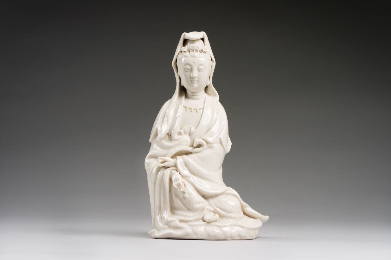 Null 中国
中国白瓷观音像，坐姿，手持如意宝杖，身穿长袍，头戴面纱。
19-20世纪。
高：26.5厘米。