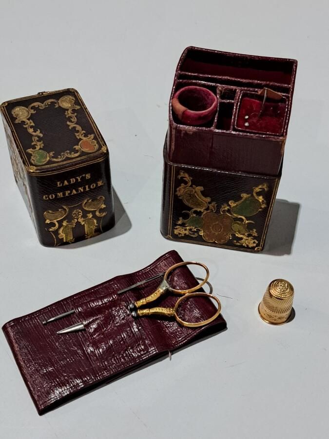 Null 在一个棕色的皮盒子里，装饰着一个女士伴侣的刻字框，一个缝纫工具，包括一个顶针和一把金剪刀。
毛重：7克。
长：11.5厘米。
(穿)。