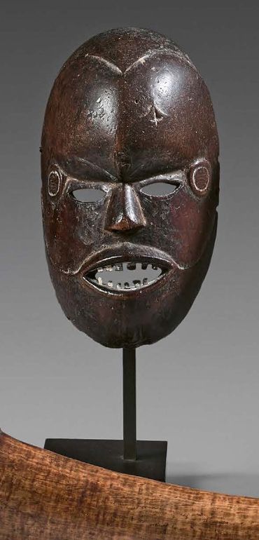 Null Boki面具，尼日利亚。
有棕色铜锈的木材，金属。
 （事故）。
高度：19.5厘米
小波基的脸，高额头下有穿孔的眼睛，嘴里有金属条的细牙。从嘴角开始&hellip;