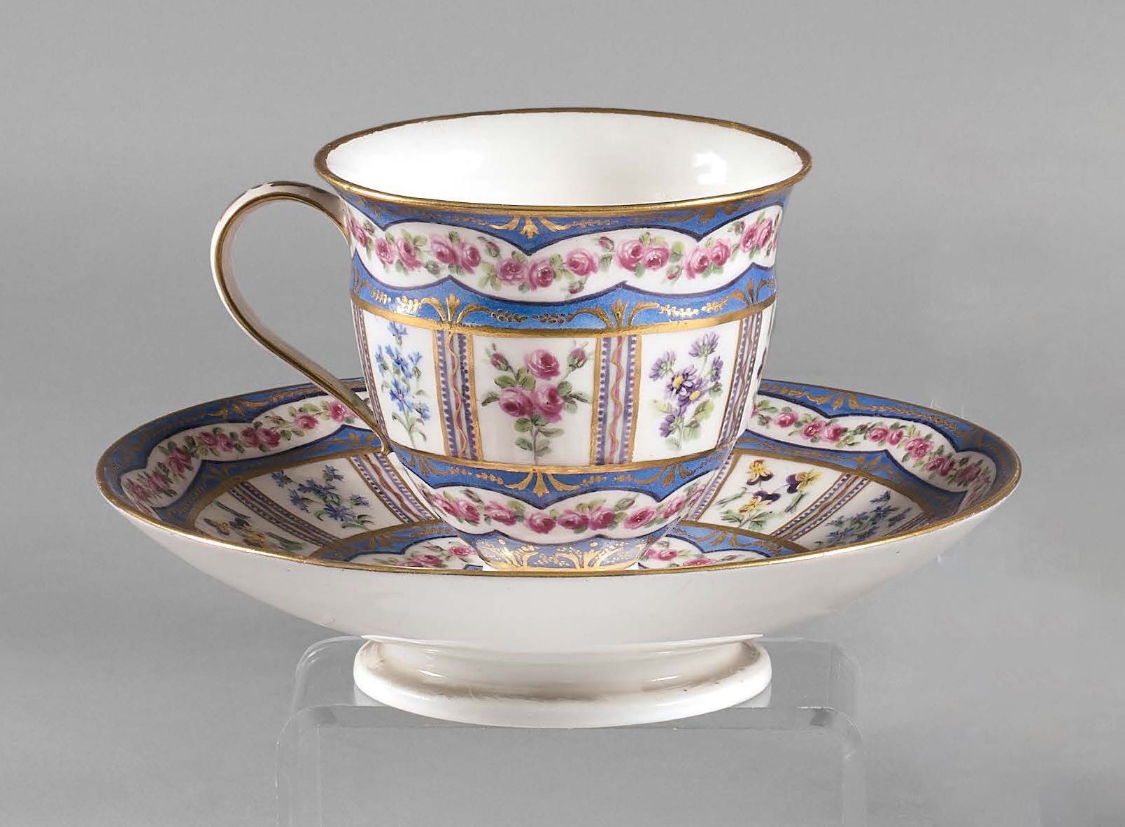 SÈVRES 小座上的伊特鲁里亚杯和它的软瓷碟子，多色装饰的三色堇、矢车菊和玫瑰花储备，与装饰有金色图案的宽大的蓝色网交替。
1791年的字母日期oo。
画家J&hellip;