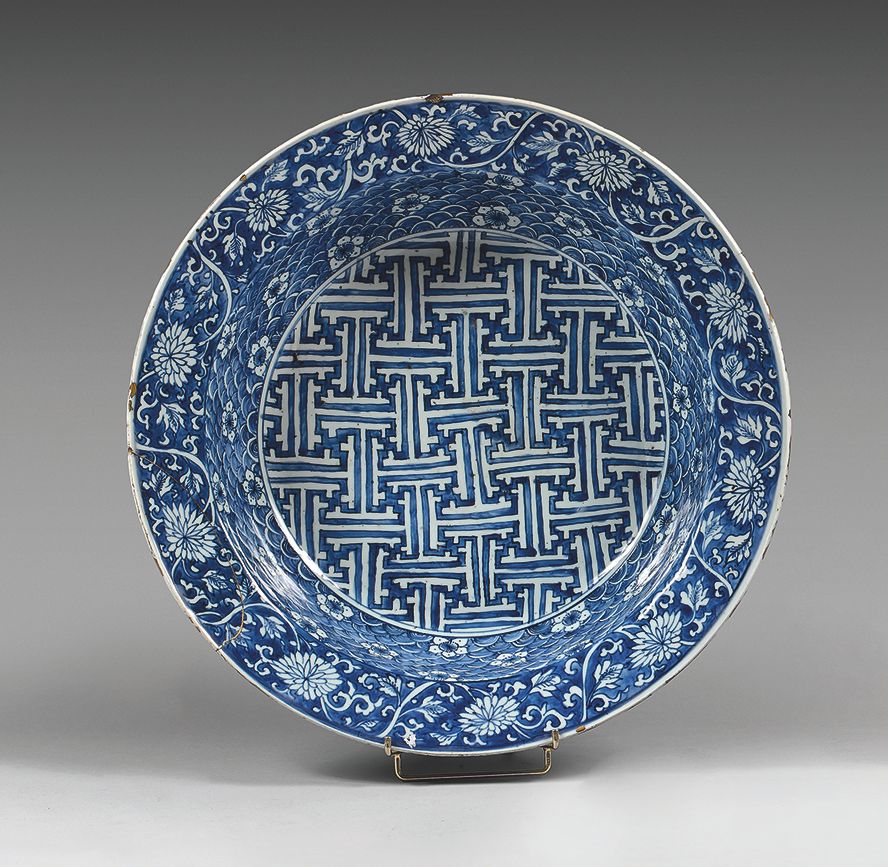 CHINE - De style Jiajing (1522-1566) 一个大的瓷盘，用蓝色釉下彩装饰，中间有一个卍字，秋天装饰着波浪背景上的樱花，边缘装饰着&hellip;