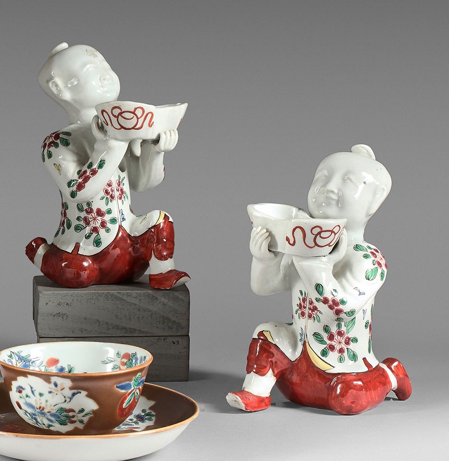 CHINE - Début du XXe siècle 
 （损坏，缺失部分，修复，缺失珐琅） 两件多色珐琅彩瓷器雕像，何氏两兄弟跪着，拿着锭子形式的杯子。
高&hellip;