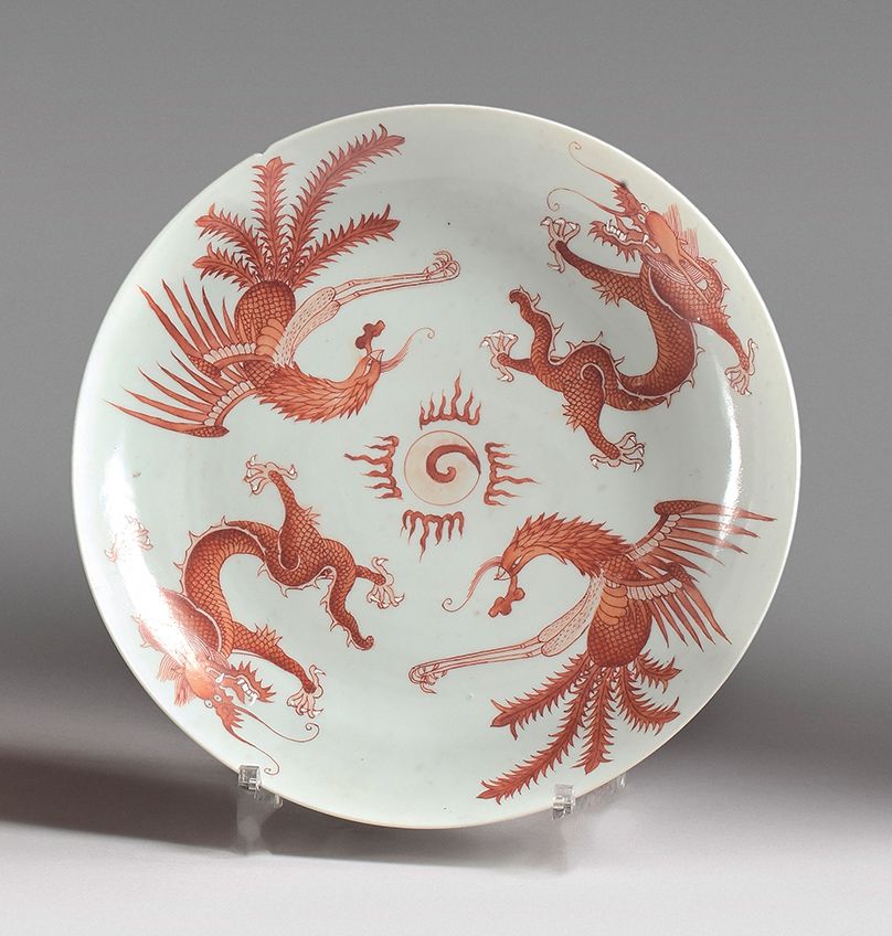 CHINE - XIXe siècle 一个铁红色的珐琅彩瓷盘，上面装饰着凤凰和龙飞舞的火焰珍珠。背面有嘉庆的天书款。
 （边缘有缺口和小裂缝，珐琅质磨损）。
&hellip;