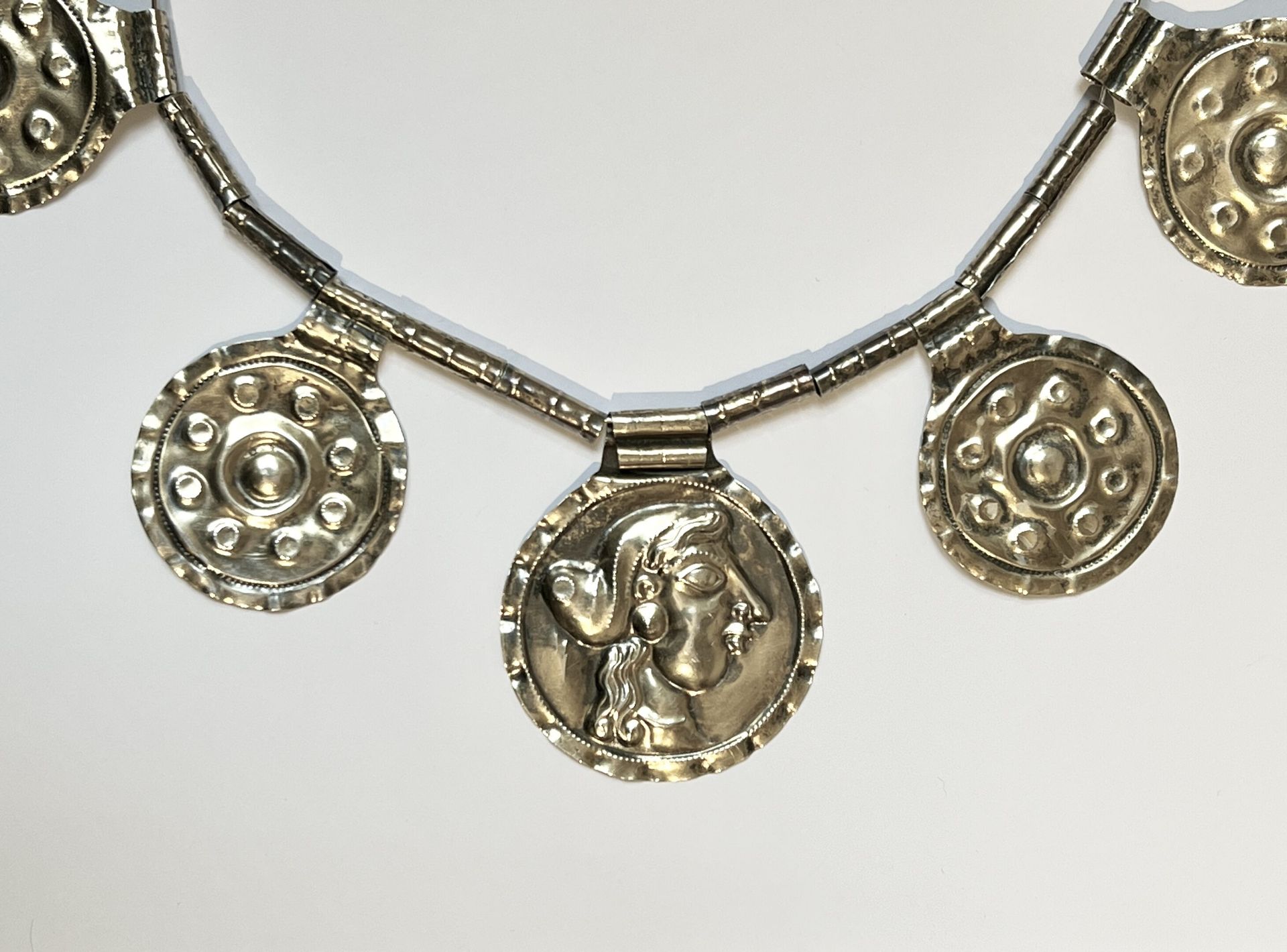 Null 由管状珠子和压印有女性轮廓和同心圆的银质奖章组成的项链。
Etruscan风格。 
重量：41.7 grs。 
总高度：22.5厘米；长度：25.5厘&hellip;
