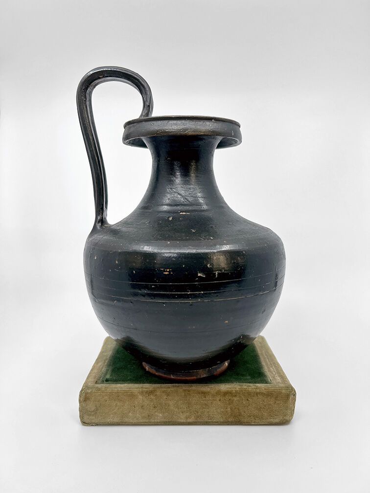 Null OENOCHOE，有凹槽的带状手柄和肩部的身体。黑色釉面的米色粘土。 
(有些缺口)。
希腊艺术，Magna Graecia。公元前4世纪 
H.27&hellip;