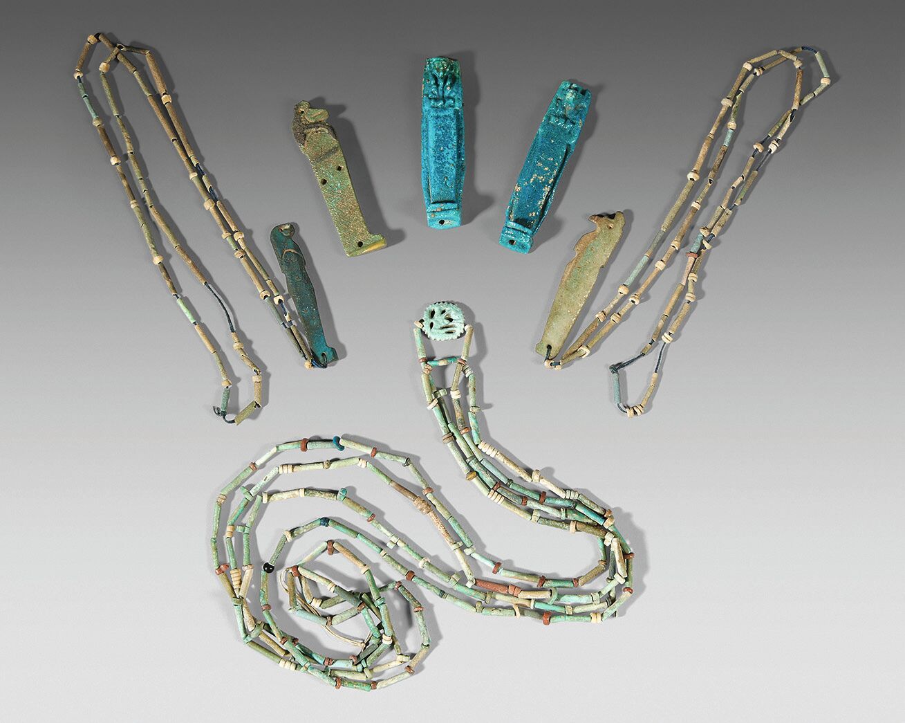 Null 拍品由四条管状珠子项链组成，其中两条饰有荷鲁斯之子的护身符，一条饰有Udjat眼睛。附有三个荷鲁斯线的盘子。 
绿色和蓝色陶器。
埃及，晚期。
尺寸：&hellip;
