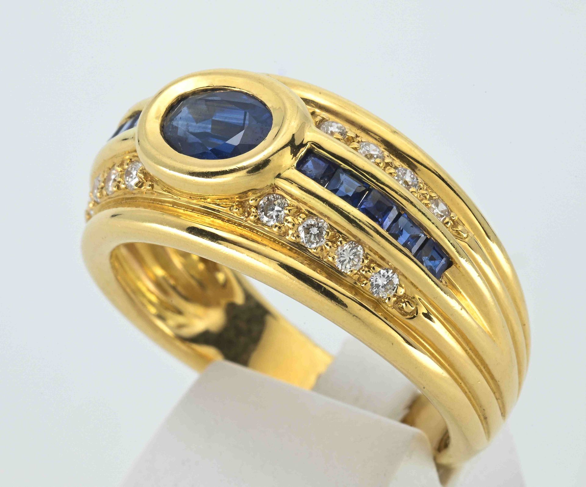 Null 黄金戒指750°°°°，装饰有10颗校准的蓝宝石
，中间是一颗封闭式镶嵌的椭圆形蓝宝石，整个肩部
，有16颗珠状切割的钻石，TDD：54。
PB：6.&hellip;