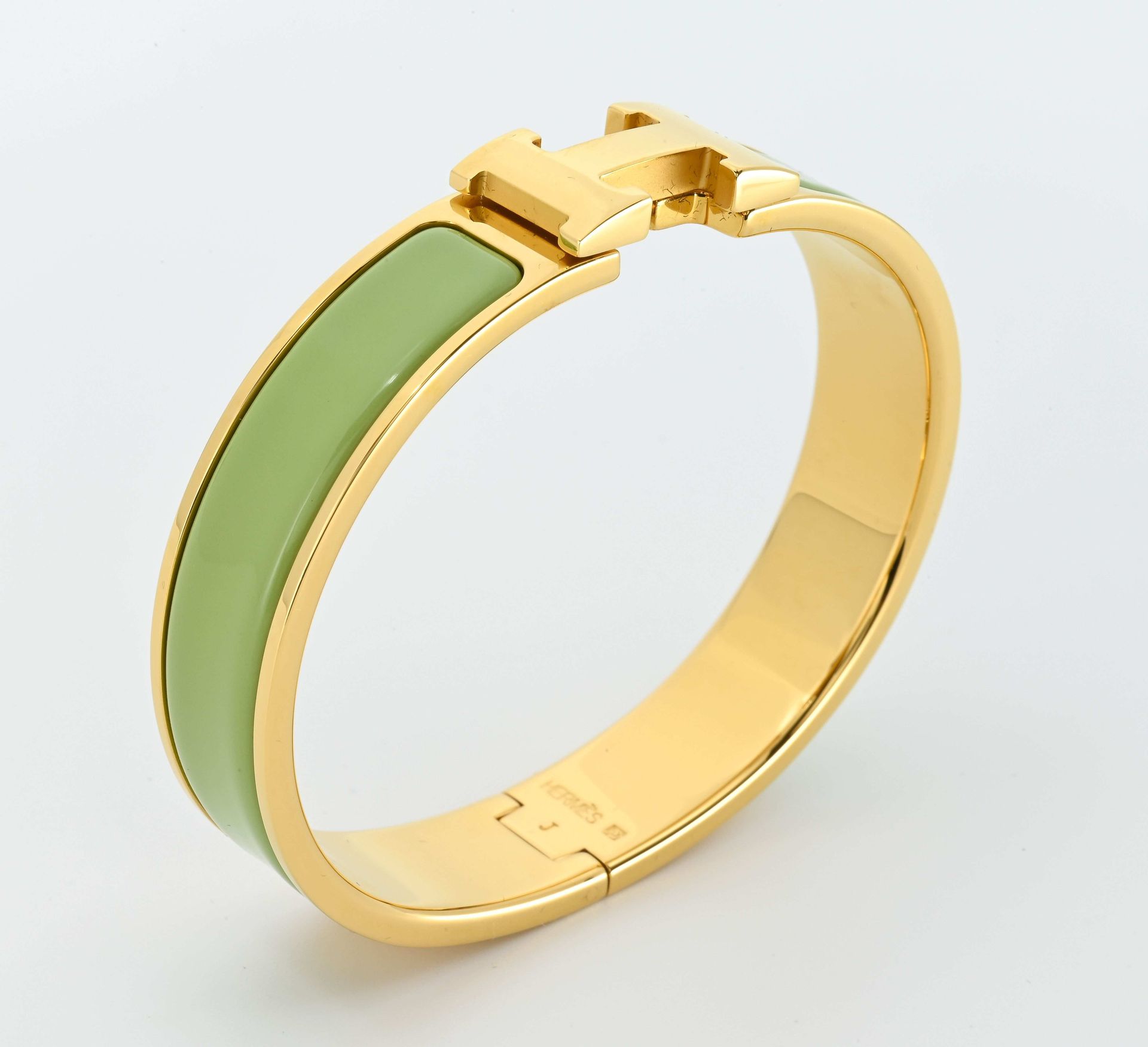 Null 
HERMES. Pulsera H-click en metal dorado y esmalte verde anís. 

Diámetro i&hellip;