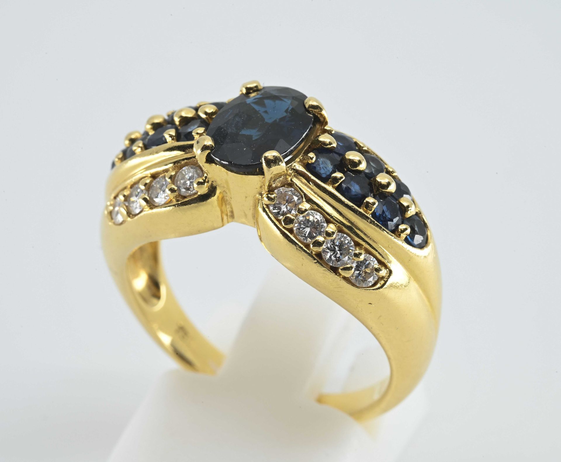 Null 黄金戒指，750°°，表圈呈结带状，
，镶有8颗圆形明亮式切割钻石，共约0.15克拉，
，14颗圆形蓝宝石和1颗中央椭圆形蓝宝石（尺寸：8 x 5.5&hellip;