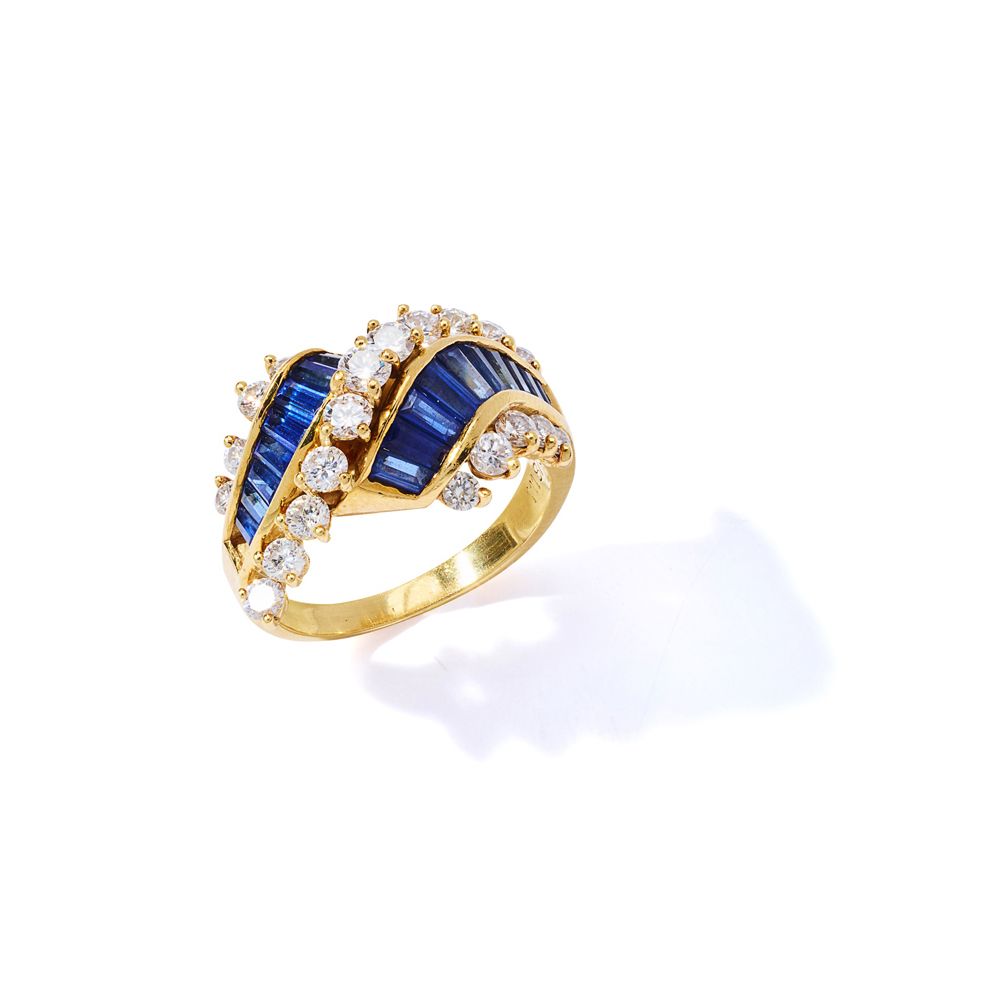 A sapphire and diamond dress ring 对立的卷轴设计，槽式镶嵌两排锥形长方形蓝宝石，在明亮式切割钻石的边框之间，一颗蓝宝石有缺陷，&hellip;