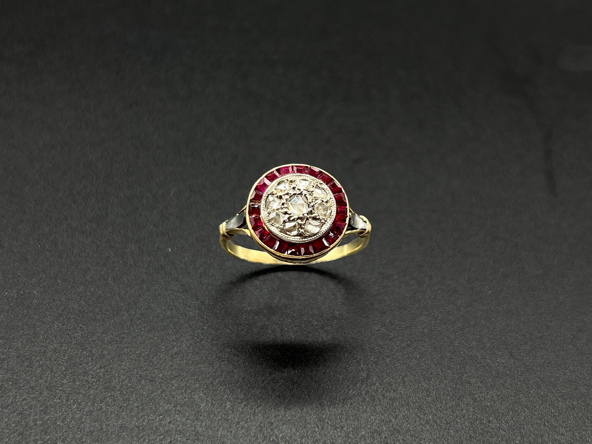 Null 18K黄金（千分之七十五）戒指，在一圈校准的红宝石中装饰有钻石的圆形表圈。

手指的周长：55。

P.毛重：3.3克。