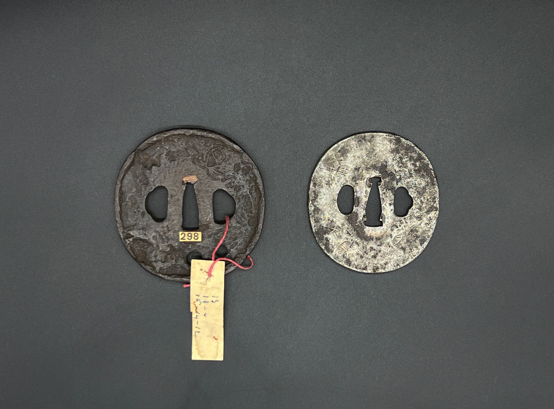 Null Set of two maru gata tsuba in tetsu, one with archaic characters decoration&hellip;