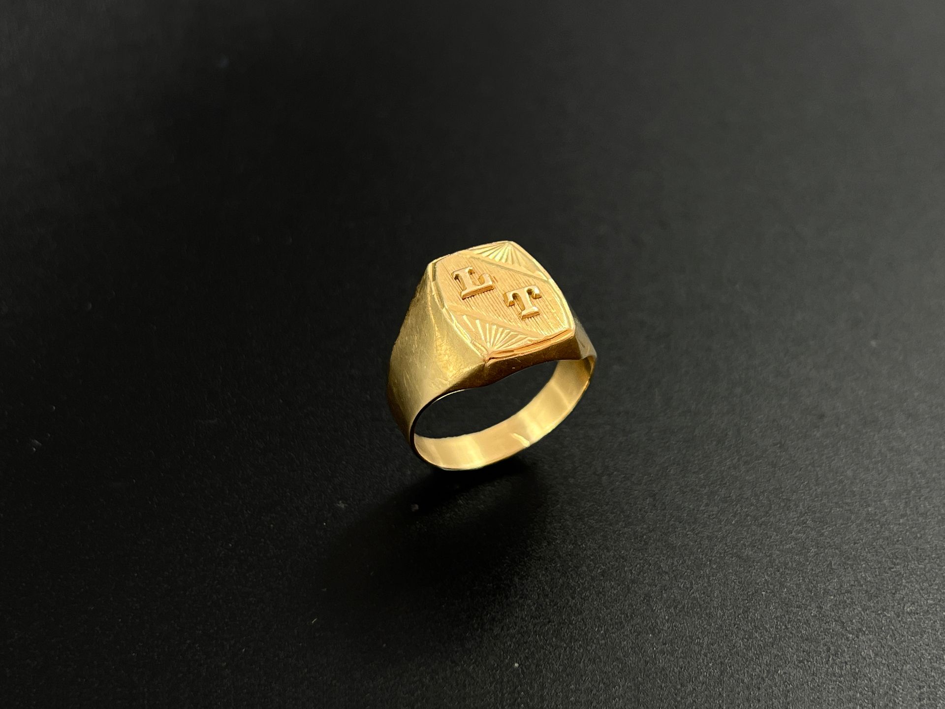 Null 标有 "L T "字样的黄金(750)戒指，背景是辐射状的图案。

重量：5.9克。