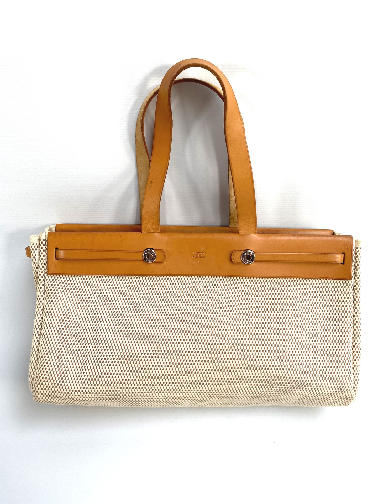 HERMES, Beige canvas and tan leather tote bag. With its …