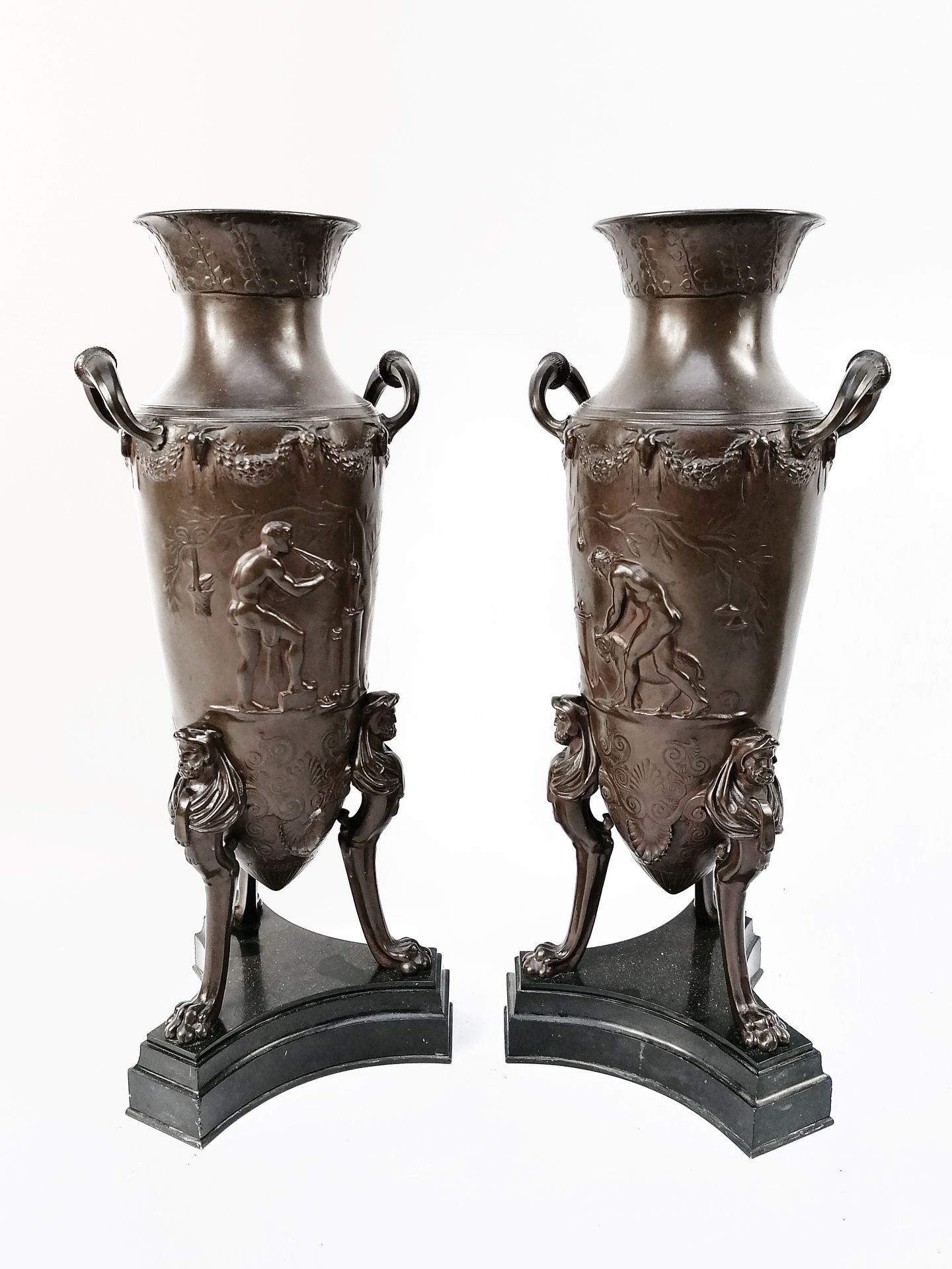 Null 费迪南-巴贝迪恩（19世纪） 
一对带凹凸不平的青铜双耳瓶，有两个把手。
丰富的花环和公羊头的楣饰，上面有古董风格的工作场景。
搁置在披头散发的男性形&hellip;