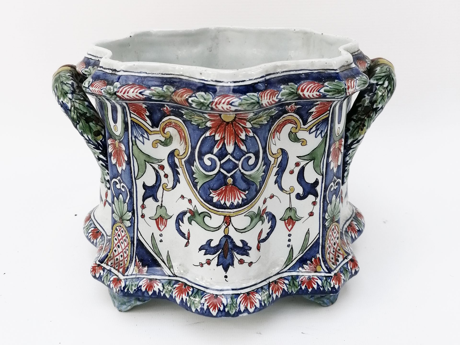 Null 描述、 
一个多叶形的陶制花盆，有两个把手，有多色的叶子、花朵和花架图案的装饰。
底座下有标记。
H.18厘米