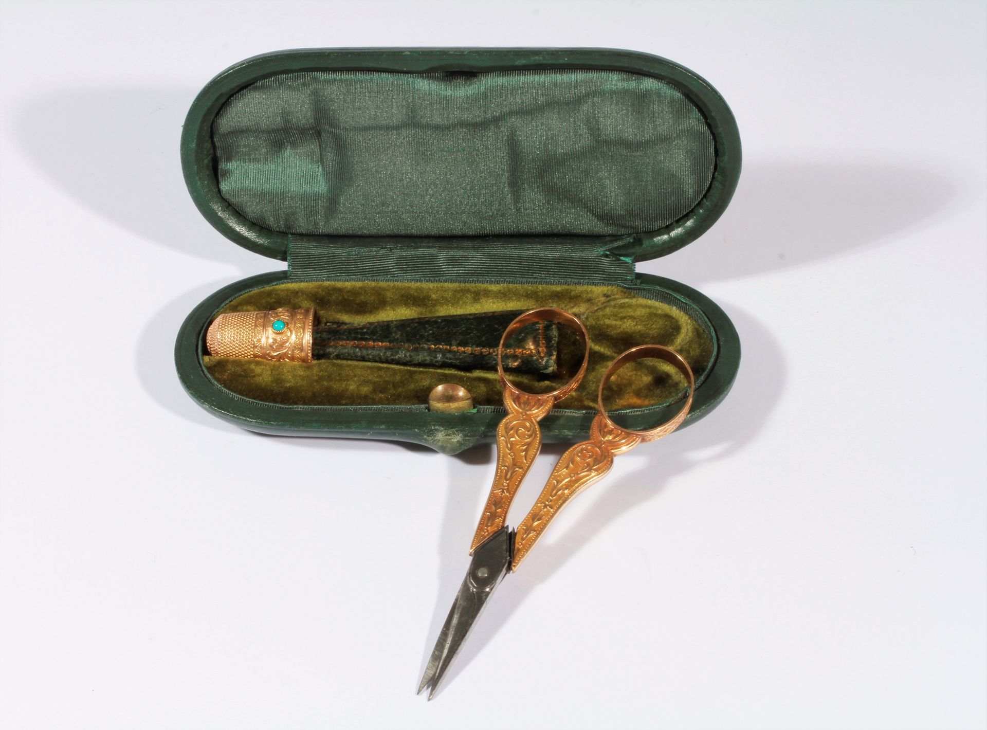 Null 绿色皮革椭圆缝纫盒，内含一把金钢剪刀和一个饰有绿松石的錾子。18K（750）金。19世纪上半叶

重量 : 17,3 g