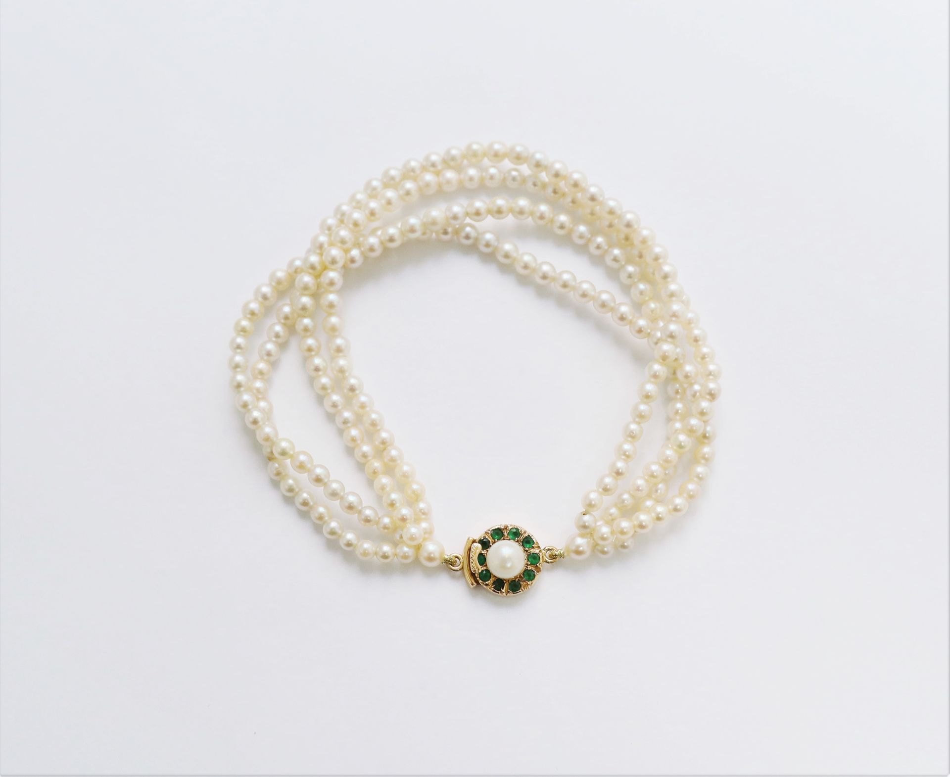 Null 手链有4排小的养殖珍珠，18K（750）金的扣子上镶嵌着一颗养殖珍珠，周围有祖母绿。长度：21厘米左右。毛重：19.1克（芯片