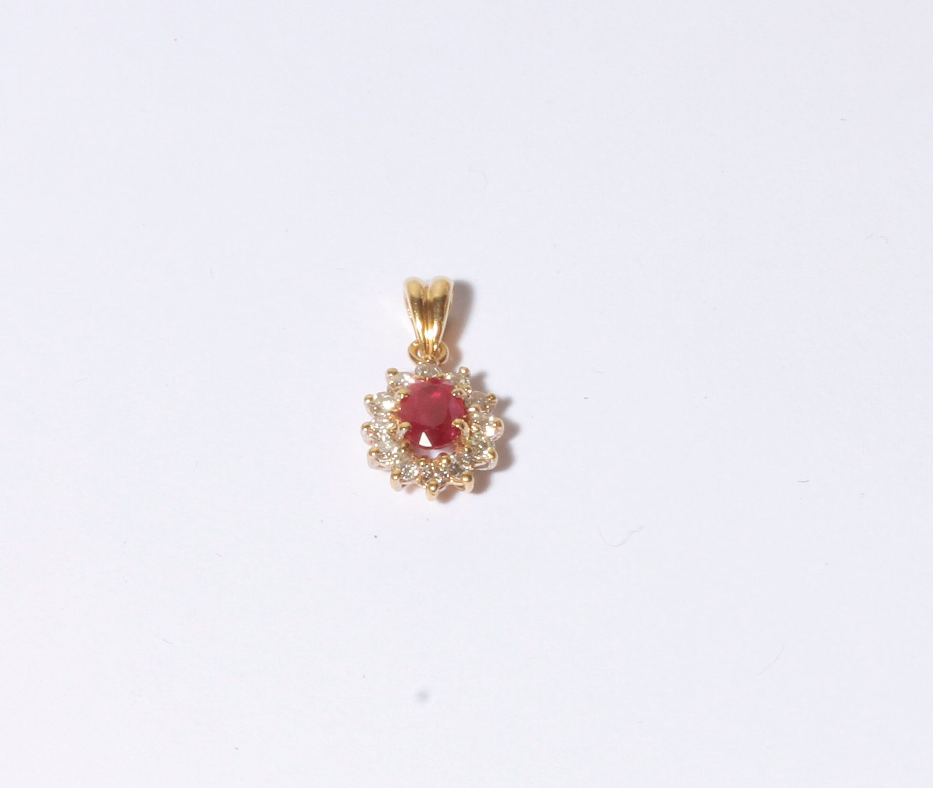 Null 18K（750）金吊坠，镶有一颗椭圆形红宝石，周围有12颗圆钻。高度：约14毫米。

毛重 : 2,6 g