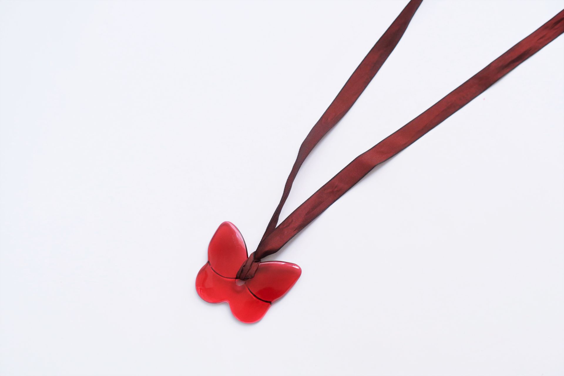 Null BACCARAT。代表蝴蝶的红色水晶吊坠，安装在一条丝带上。签名。在它的袋子和箱子里