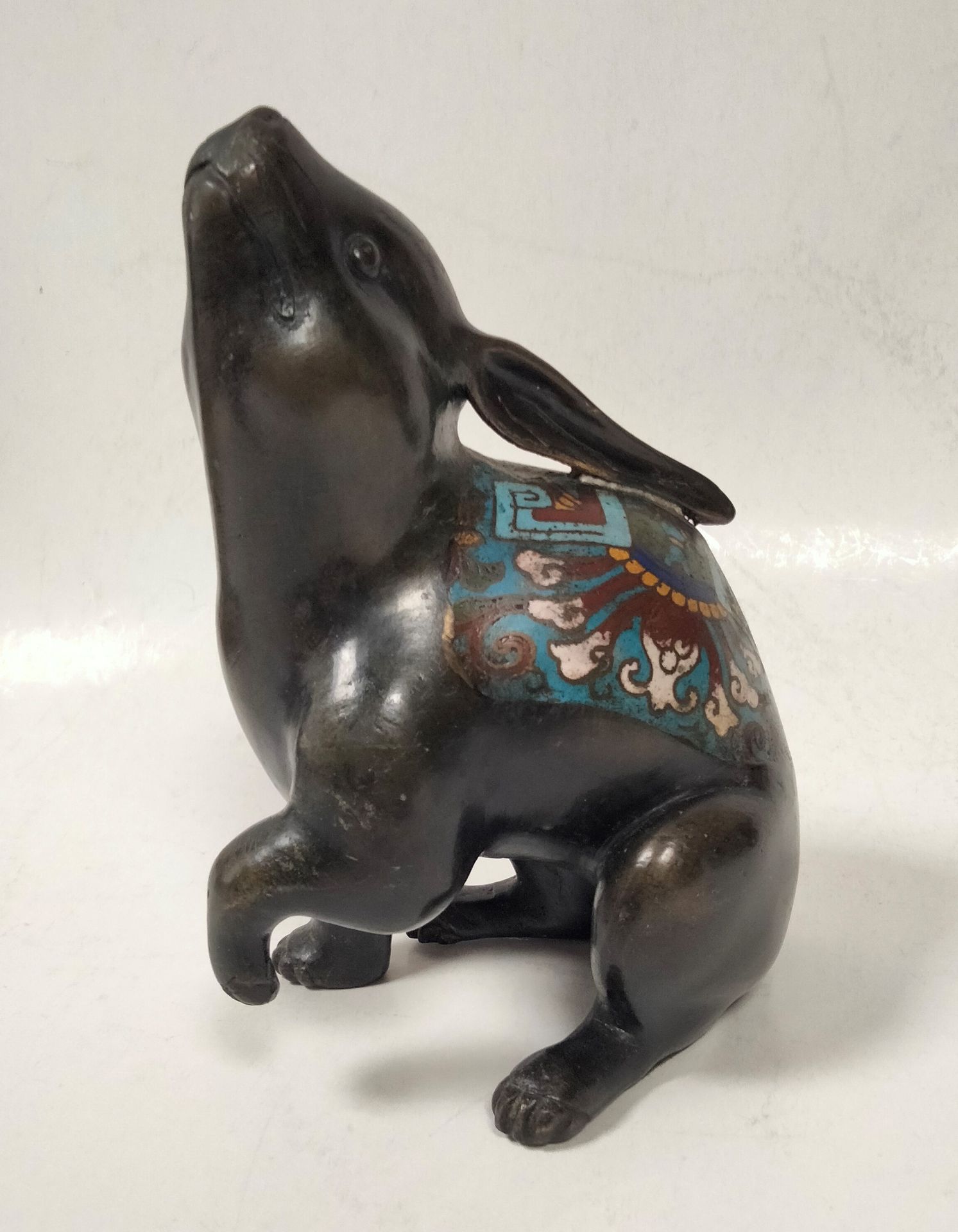 Null 兔子的青铜主题，日本，约1900年用后腿坐着
，背面是掐丝珐琅的多色几何和叶子
的图案。
 
高度：21厘米珐琅质磨损
。
