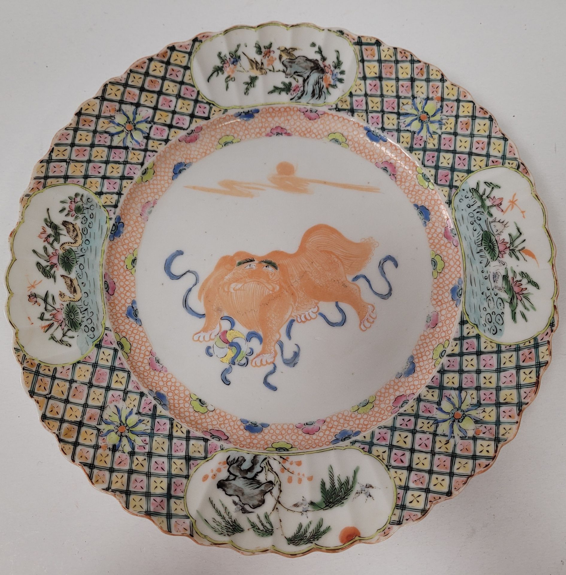 Null 珐琅彩瓷盘，中国，Compagnie des Indes，18世纪
中央有一个石狮的多色装饰，边缘有四个储备
。
边缘是弯曲的。
直径：25厘米