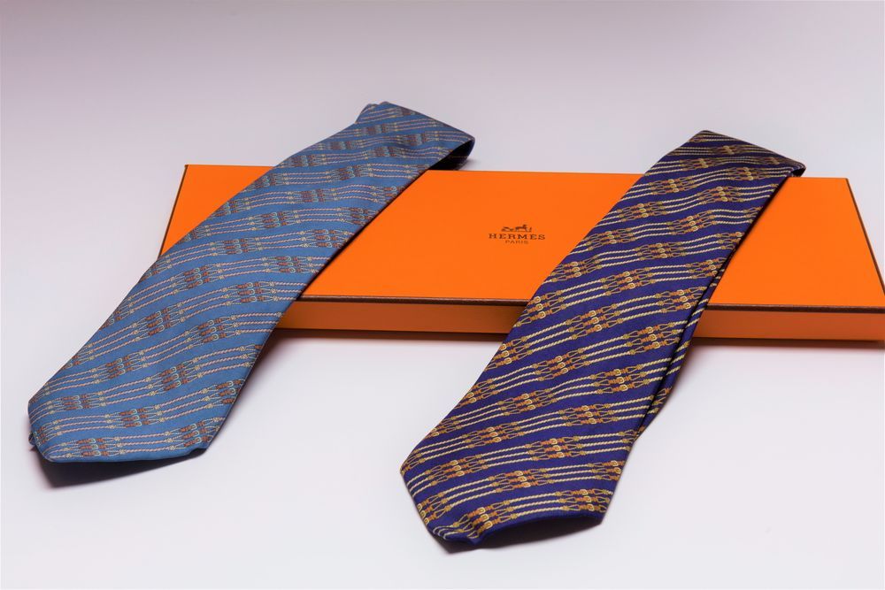 Null HERMÈS
2 Cravates en soie fond bleu à motifs de rênes. Boîte.
