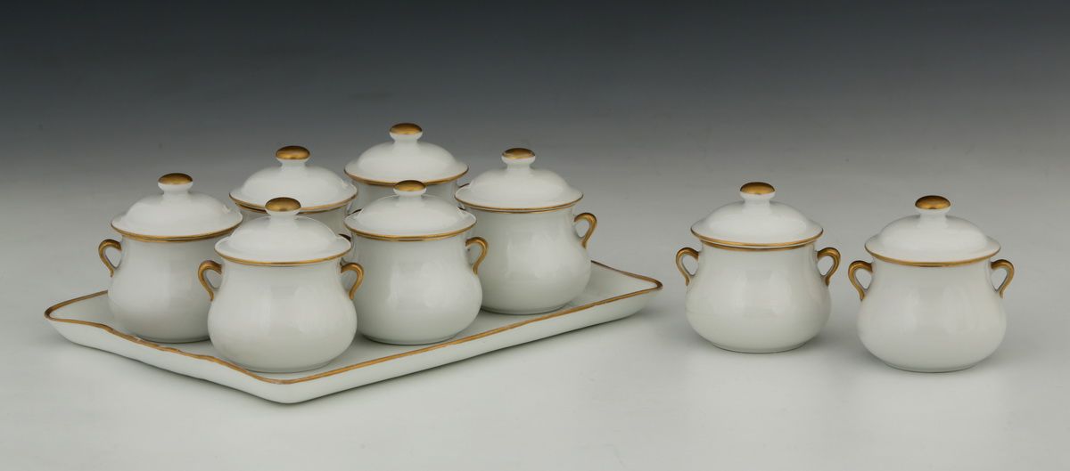 Null 9件20世纪初的白色和金色的奶油瓷器套装

- 8个带手柄的有盖锅，旋钮式锅盖

H.7,5 cm

- 1个带弧形手柄的长方形卡巴雷特托盘，可放置6&hellip;