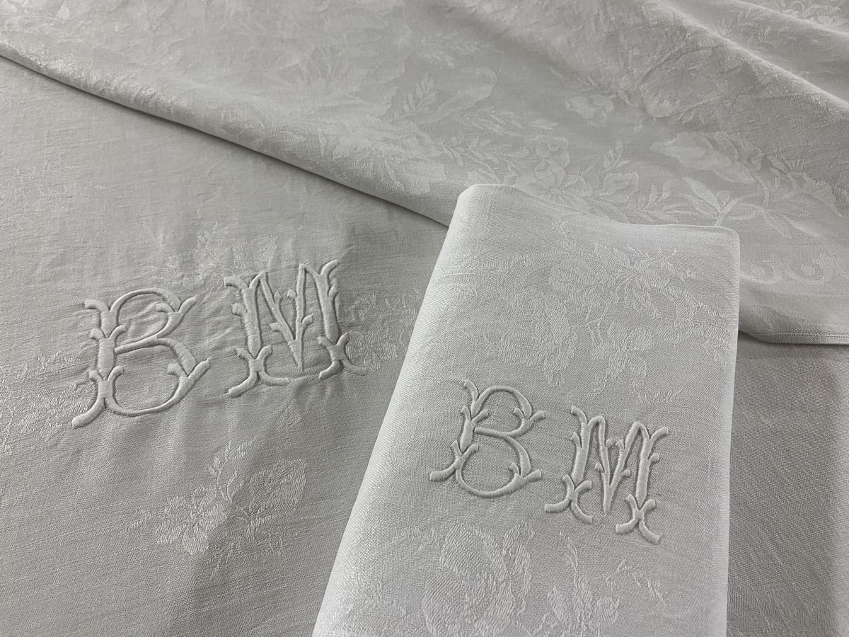 Null 19世纪末在白色棉质大马士革上绣有玫瑰和花朵的卷轴，以及两个BM的字母图案的大方形床单和8条毛巾。

300 x 174 cm

TBE (原样)