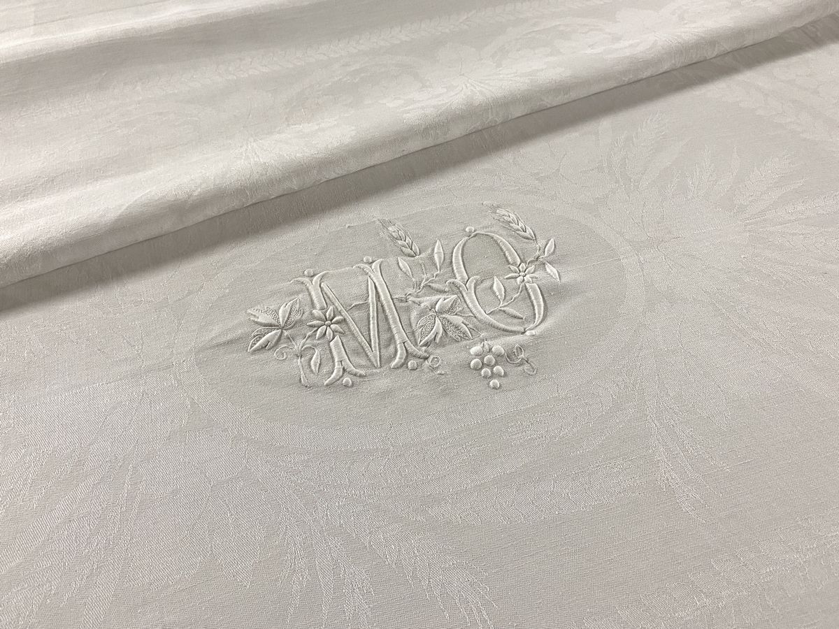Null 19世纪末在白色棉质大马士革上绣有大黄蜂针法的MO字样，中央有叶子图案，麦穗，藤蔓和花朵。

232 x 184 cm

BE（小修）