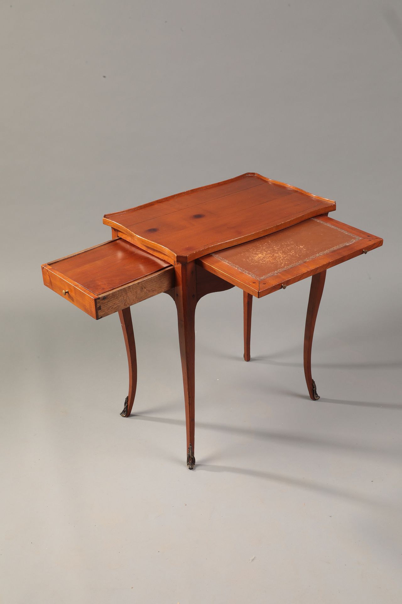 Null 浅色木质写字桌，棕色皮革桌面

并在侧面有一个抽屉的情况下打开，露出一个挡板。

凸形腿，带青铜套筒

19世纪

H.68厘米，宽58厘米，长38厘&hellip;