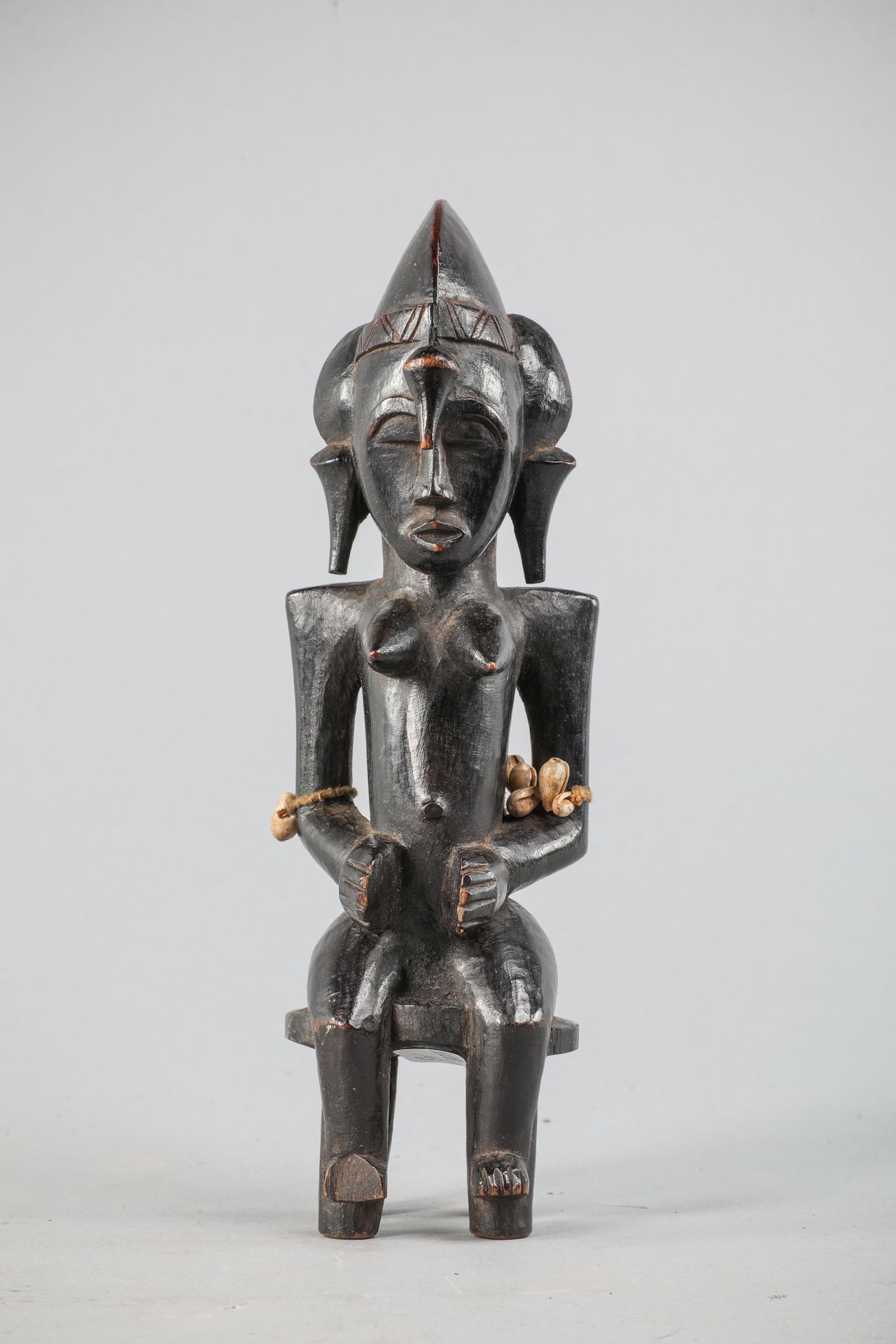 Null 塞努弗女性形象，象牙海岸，描绘的是坐姿。可能是手杖的顶端。木头，金属，牛耳壳，黑色漆面。高24.5厘米。