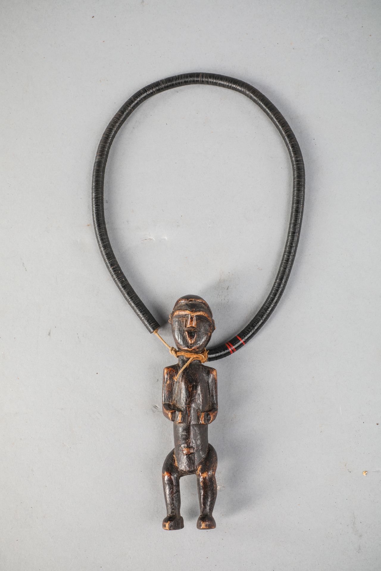 Null Lwalwa项链，刚果，其吊坠是一个带有几何线条的小字。木质，有黑褐色的铜锈，角质珠子。宽35厘米，人物高11厘米。