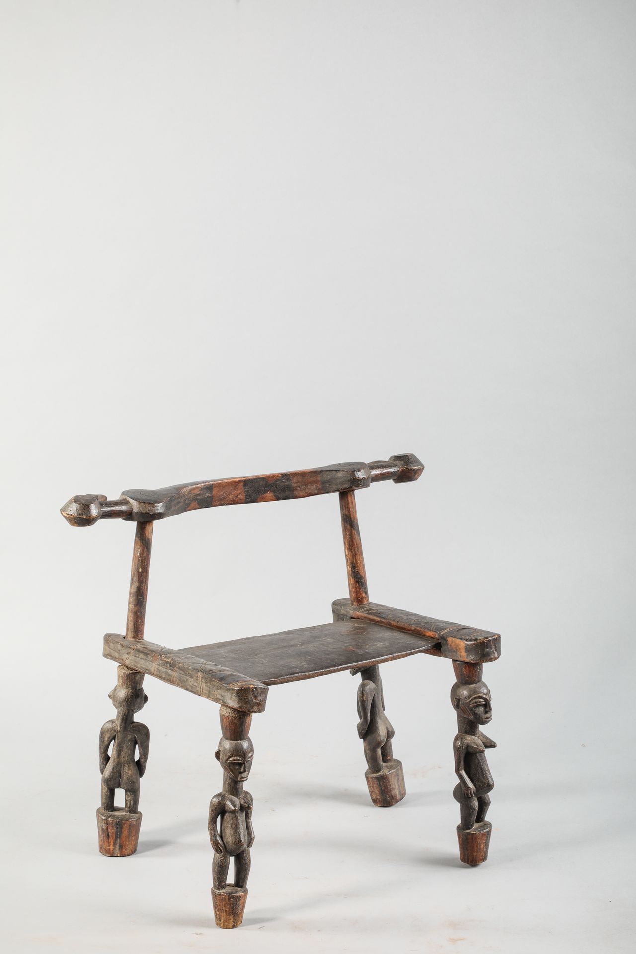 Null 传统的塞努弗座椅，象牙海岸，腿上雕刻着女性和男性的形象，靠背的两端是犀鸟的头部形状，侧面有雕刻的线条装饰。


具有棕黑色漆面的木材


高度63厘米