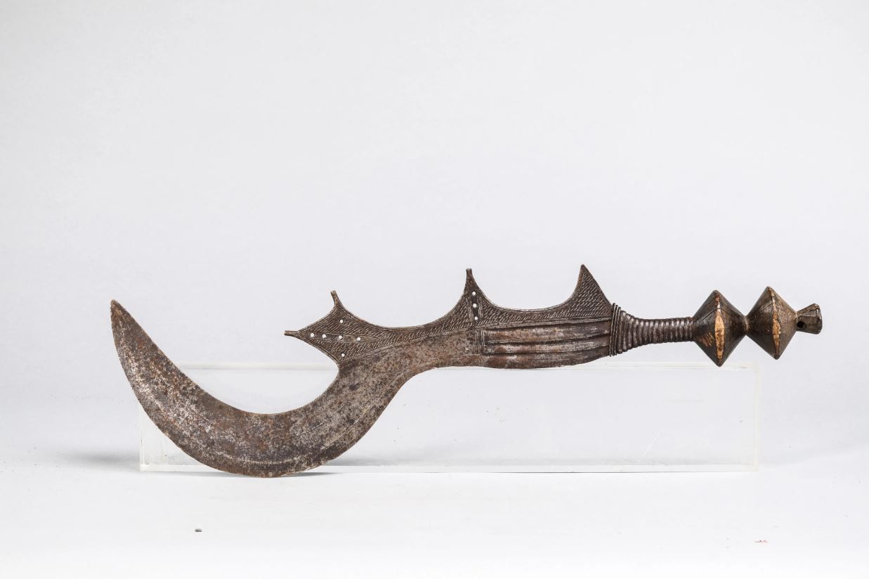 Null 美丽的Ngombé剑，刚果。刀身沿用了美丽活泼的设计，镂空的小圆圈，全身都有精美的雕刻装饰。木头，锻铁，锤击铜线。长69厘米。