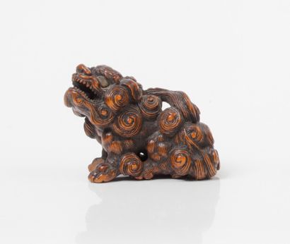 null Netsuke en bois rehaussé de brun, représentant un shishi assis, la tête dressée,...