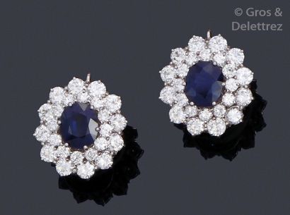 null Pair of white gold earrings, each adorned with an oval sapphire in a double...