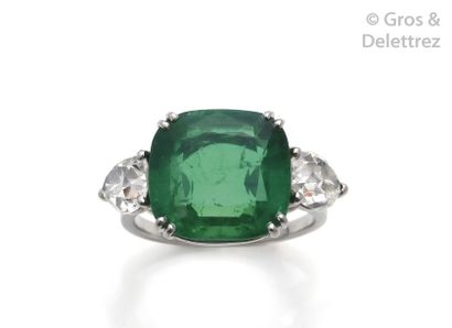 null Platinum ring, adorned with a cushion-cut emerald set with pear-cut diamonds...