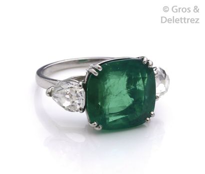 null Platinum ring, adorned with a cushion-cut emerald set with pear-cut diamonds...
