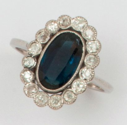 null Ring " Fleur " in platinum, decorated with a blue stone in a ring of old cut...