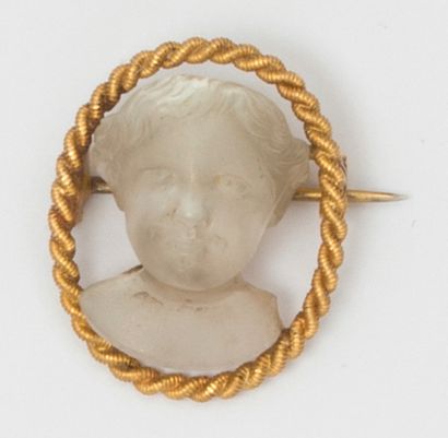 null Broche en or jaune torsadé, ornée d’un profil d’enfant en pierre de lune sculptée....